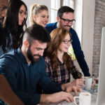 team di lavoro in ufficio, difronte ad un laptop