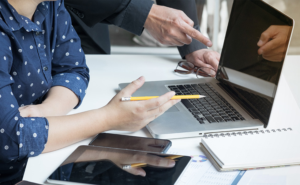 immagine generica, tavolo da lavoro con laptop e due persone visibili parzialmente